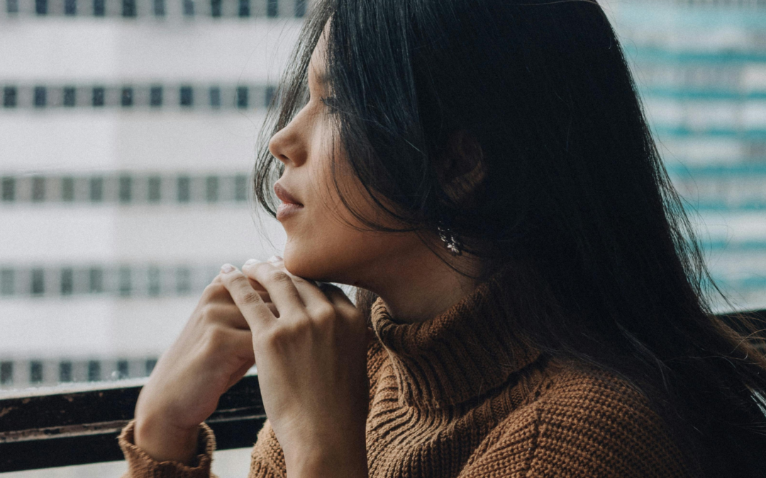 Woman looking out a window thinking.